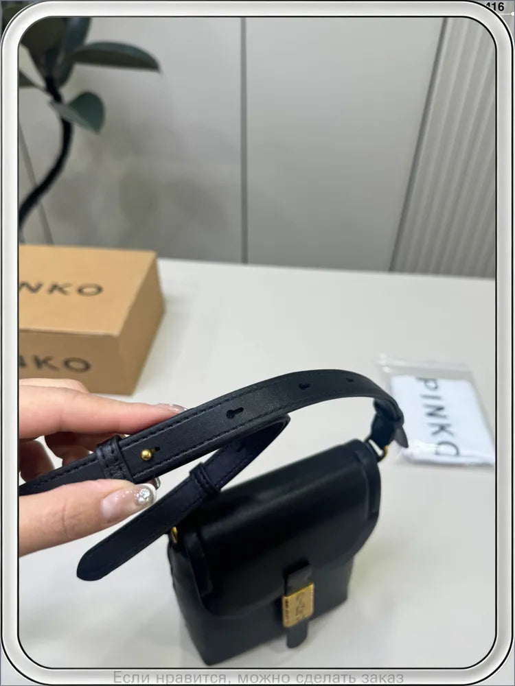 Qara mini çantanın qızılı metal detalı, yaxın plan